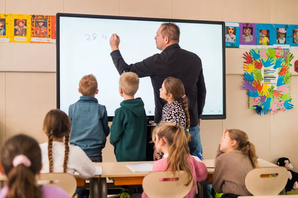 Leerkracht schrijft op een interactief CTOUCH scherm in de klas / enseignant écrivant sur un écran interactif en classe
